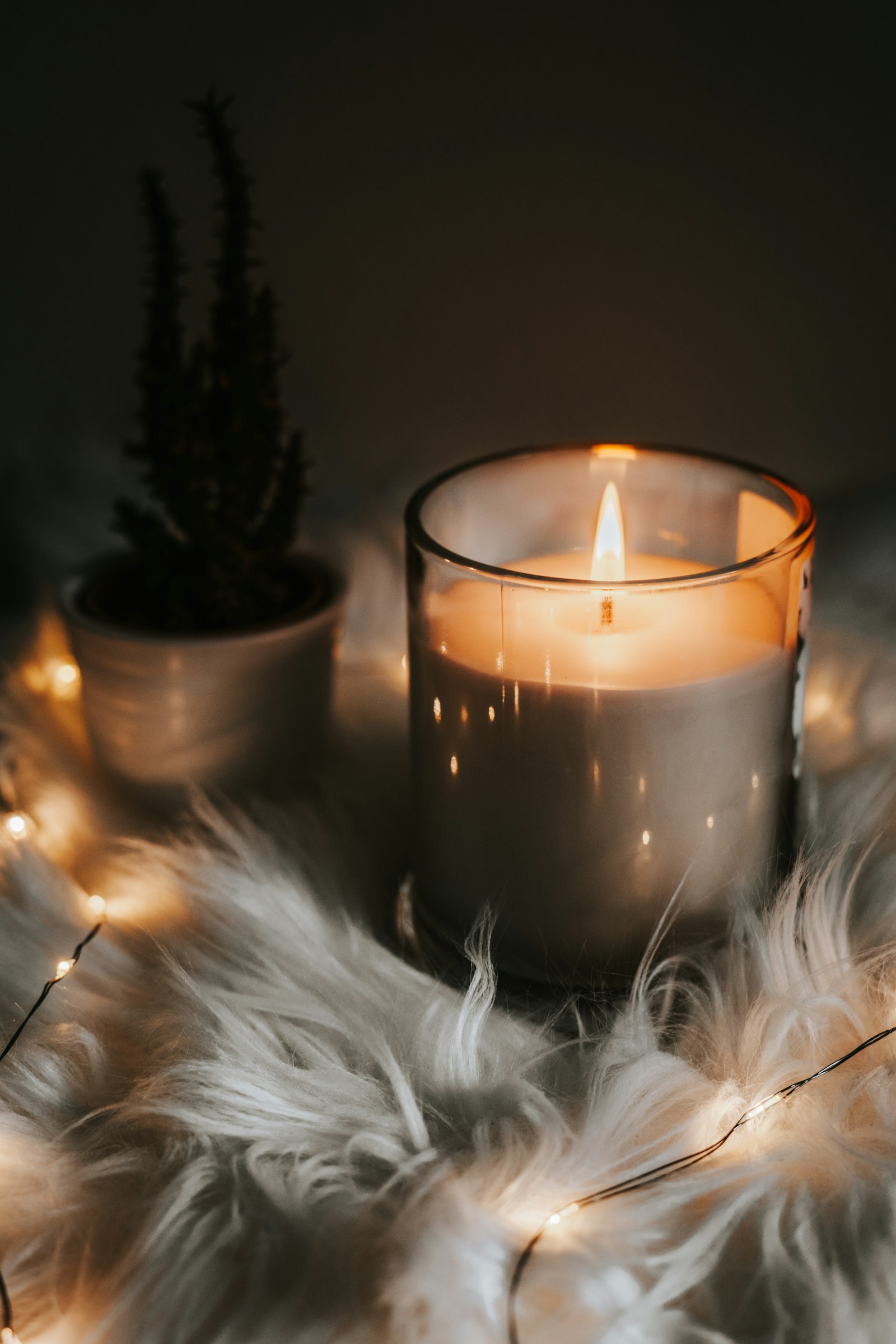 Hand-poured ribbed ceramic scented candle with glowing flame on natural linen